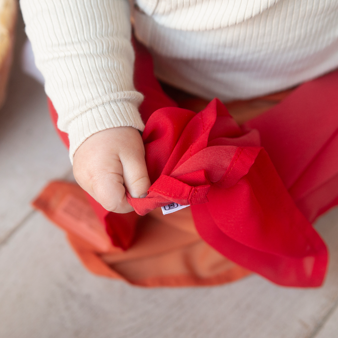 baby speelt met rode speeldoek